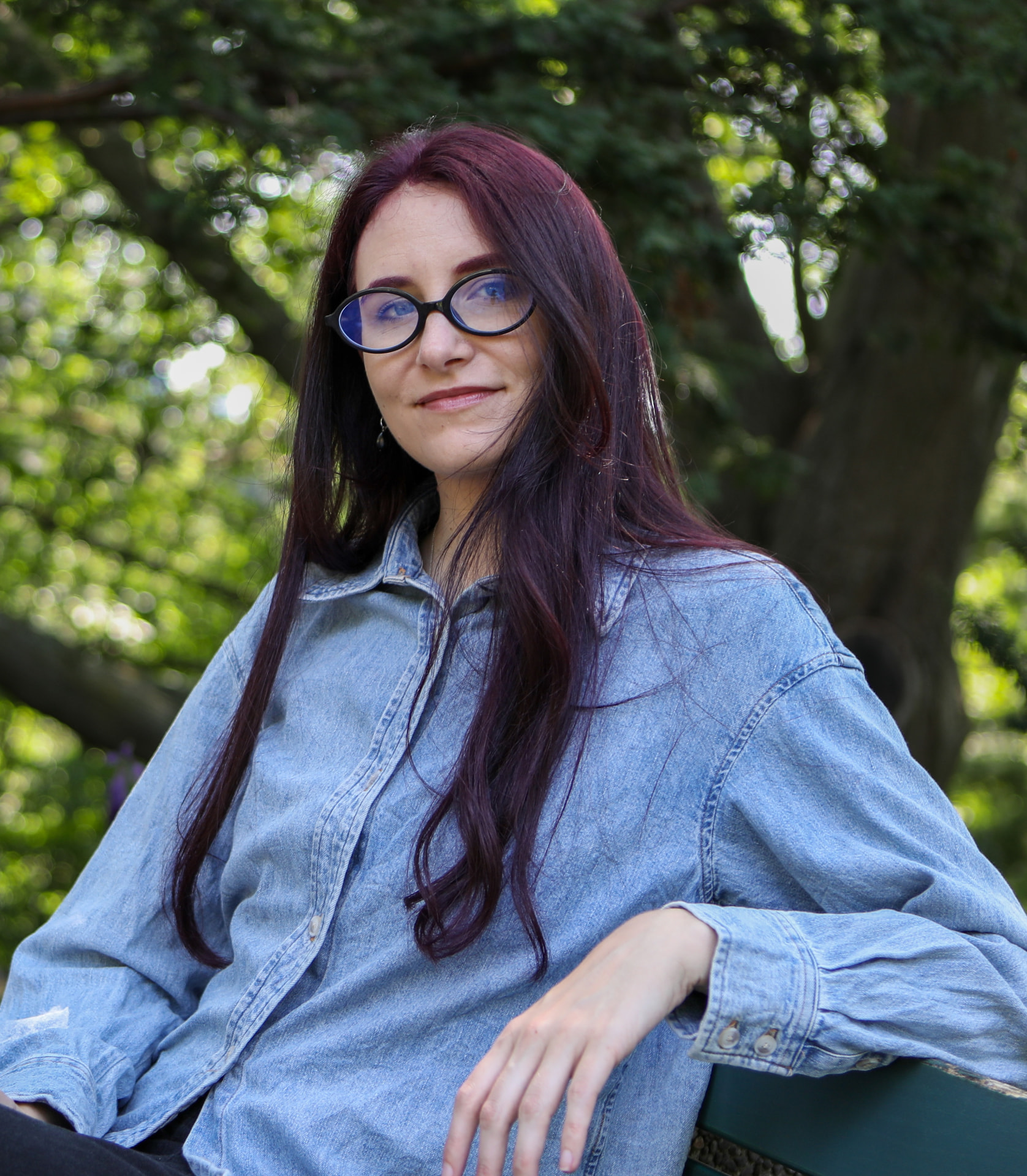 Aliya Lucatch seated outdoors on a bench beneath trees